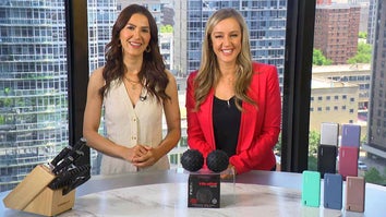 Two women standing behind a table displaying knives, massage balls, and powerbanks